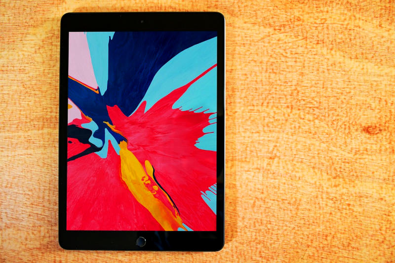 ein Tablet mit einem abstrakten Hintergrundbild auf einer Holzplatte