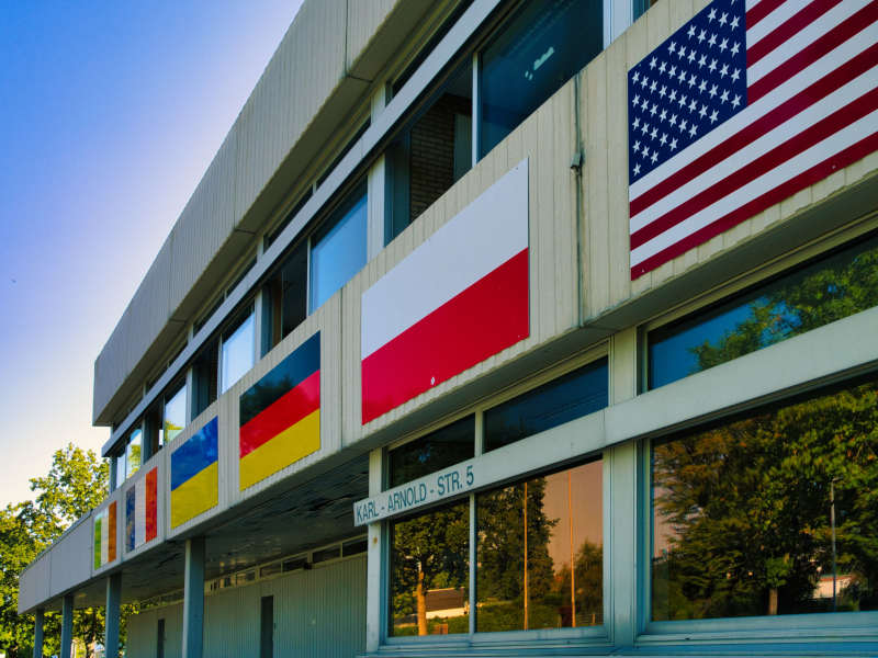 Westfassade des Burgau-Gymnasiums mit Flaggen von Italien, Frankreich, Ukraine, Polen und USA