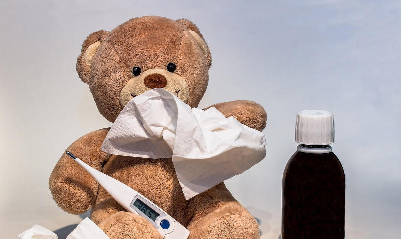 Ein Teddybär mit Taschentuch, Fieberthermometer und Medizin