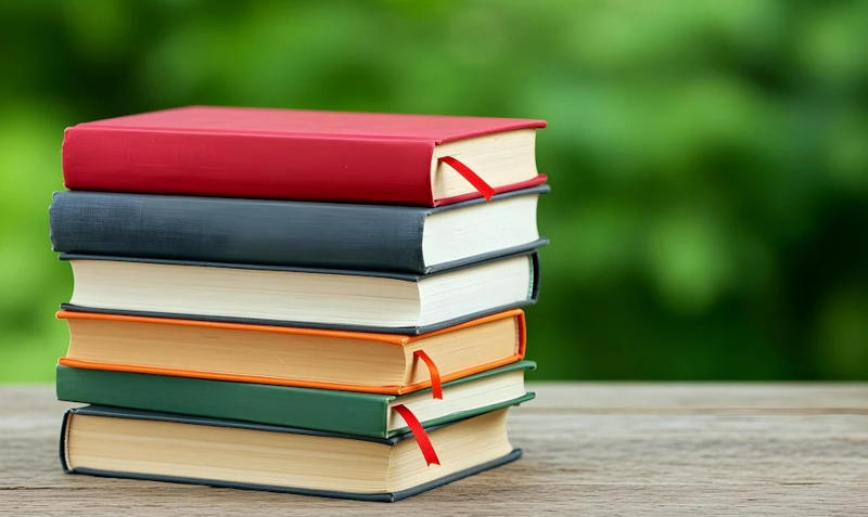 Ein Stapel mit Büchern vor einem grünen Hintergrund