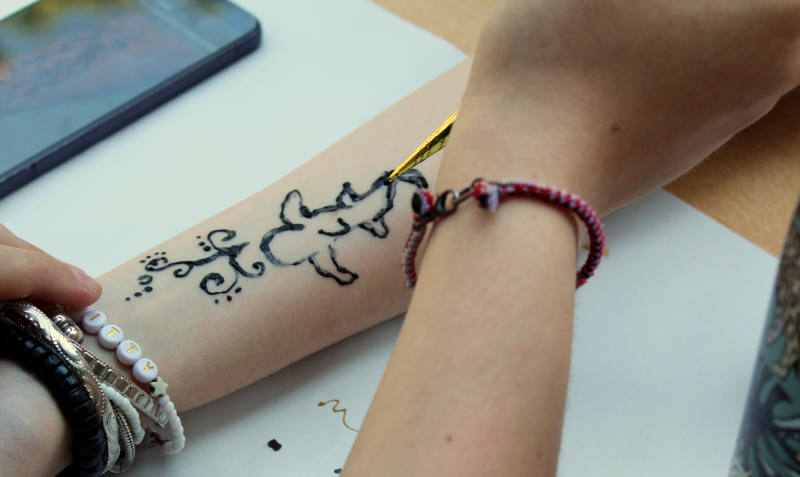 Ein Arm wird mit einem Tattoo bemalt